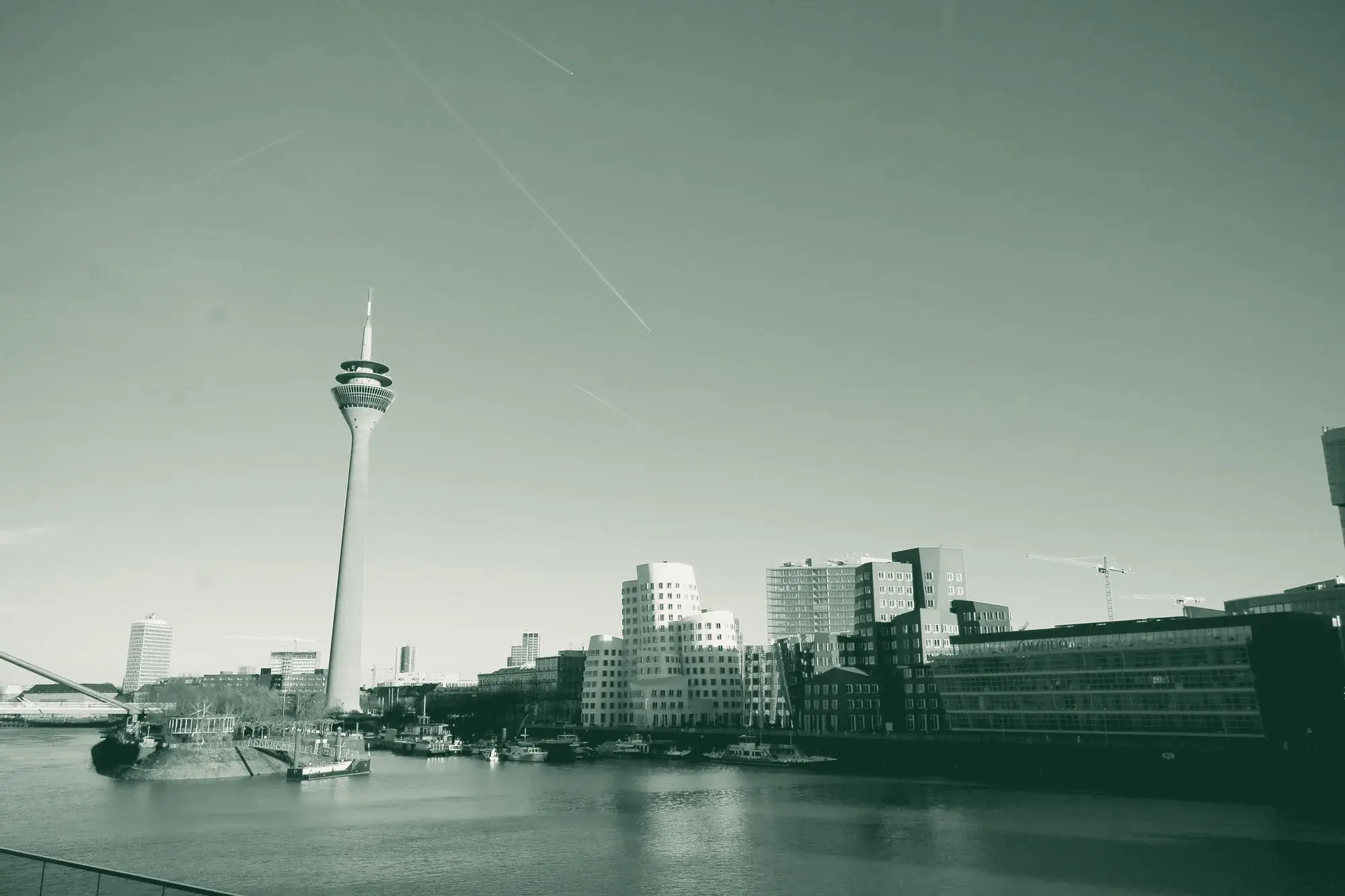 Der Düsseldorfer Medienhafen mit Rheinturm und den geschwungenen Gehry-Bauten, in den Farben der Kanzlei eingefärbt.